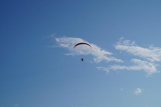 Paraglider flying against the blue sky, extreme sports.