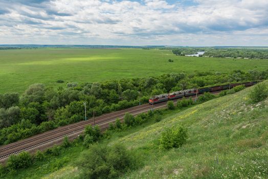 Freight train with locomotives passing by rail in Russia, along the typical Russian landscape, top view.