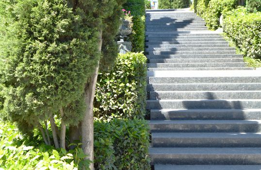 Marble staircase leading to the sea along the cypress trees in the Park on a Sunny day.