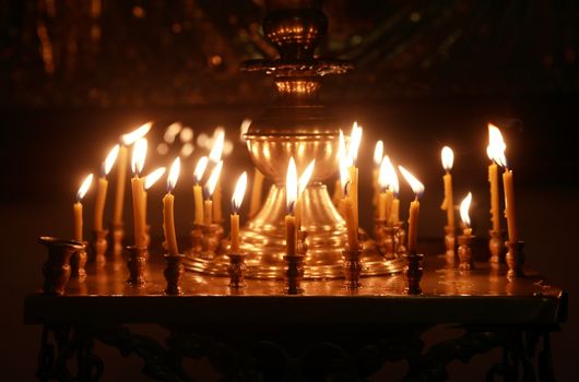Christianity church interior. Set of lighting candles on dark background