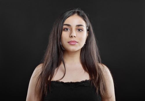 Beauty portrait of a young girl who stands on a black background in the Studio dressed in a black t-shirt