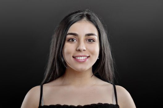 Beauty portrait of a young girl who smiles and stands on a black background in the Studio