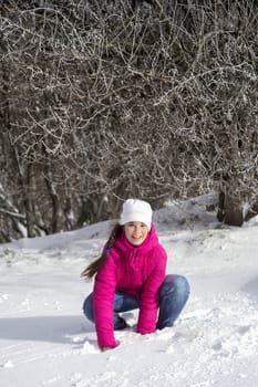 Portrait of a teenage girl in the winter outdoors. playing with snow in the forest.