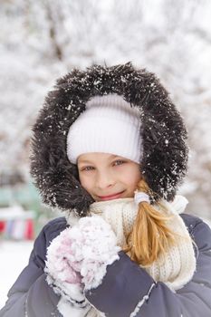 Happy child girl playing on a winter walk in nature with snow