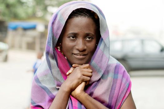 smiling young veiled woman praying hands clasped.