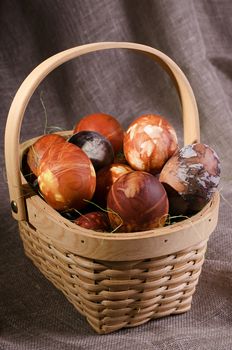 Easter eggs. Brown painted eggs in the basket on brown background.