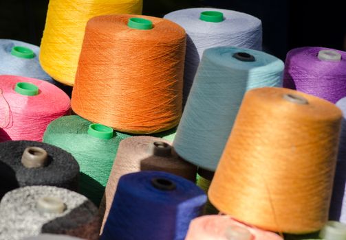 Colorful thread spools, one above the other. Coils with colurful threads.
