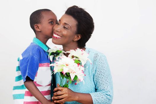 child wishes good mothers day to his mother by offering her a flower.