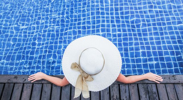 Woman in hat relaxing at the pool in resort