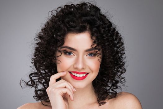 Fashion studio portrait of beautiful smiling woman with curls hairstyle. Fashion and beauty