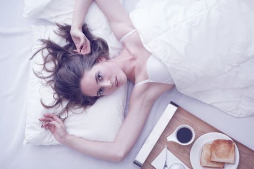 Beautiful young woman having breakfast in bed