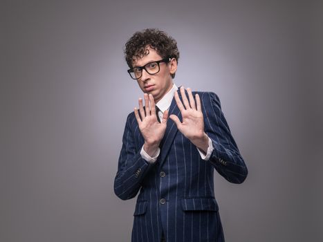 Shocked funny man in suit showing rejection sign and looking at camera. Uninterested businessman making stop gesture. Refusing concept