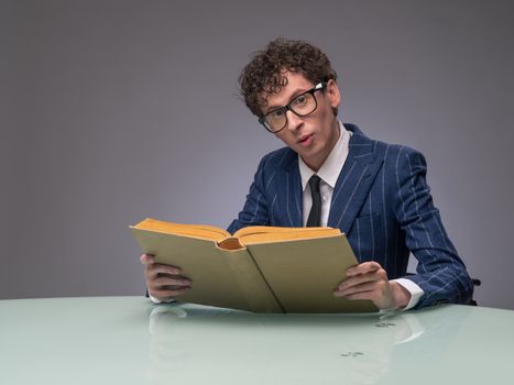 Funny man in suit and glasses reading old book and surprised