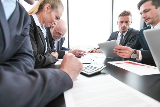 Group of people in office at business meeting working with documents reports and computers