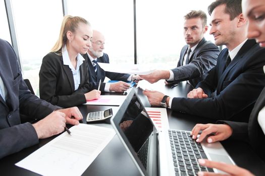 Group of people in office at business meeting working with documents reports and computers