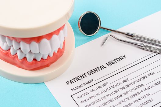 Dental history form with model tooth and dental instruments. Dental health and teeth care concept.