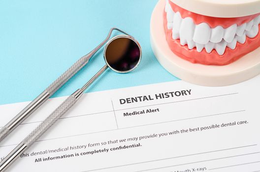 Dental history form with model tooth and dental instruments. Dental health and teeth care concept.