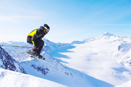 Jumping skier at jump with alpine high mountains