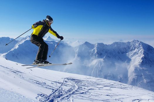 Jumping skier at jump with alpine high mountains