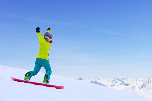 Girl snowboarder running down the slope in Alpine mountains. Winter sport and recreation, leisure outdoor activities. Image of excited screaming young woman enjoyment concept