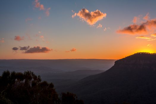 Sunset behind the escarpment cliffs of the Blue Mountains, withdrawing its light from the valley leaving them just shadowy silhouettes at days end