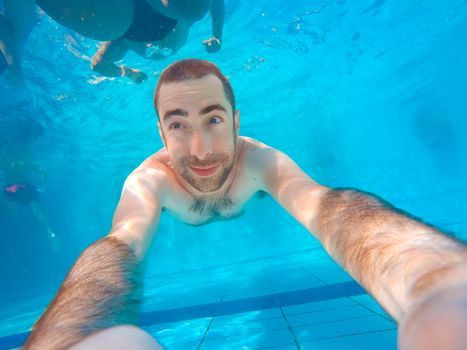 Young handsome man diving underwater in a swimming pool.