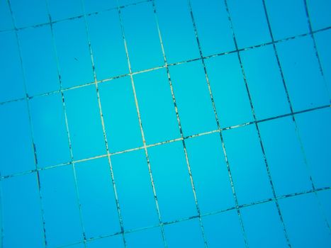 Texture of blue tiles on the bottom of the swimming pool.