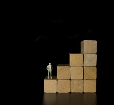 Wood block stacking as step stair with man on top of the career, Ladder career path concept for business growth success process on black background