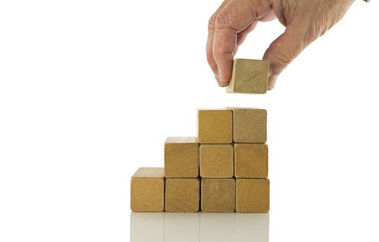 Hand putting wood black on top and arranging wood block stacking on top with wooden table, Business concept for growth success process