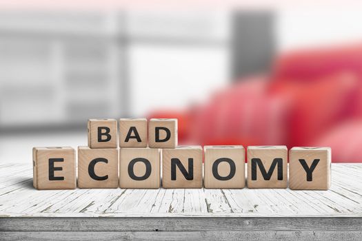 Bad economy sign on a wooden desk in an office with red color in the background