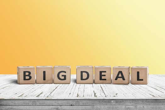 Big deal sign made of wooden cubes on a desk with a yellow wall in the background