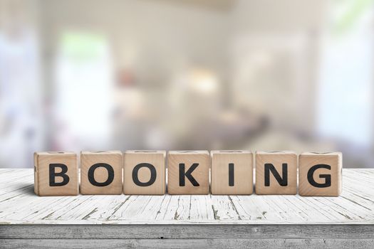 Booking sign on a wooden desk in a room with a bright blurry background