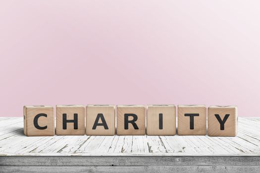 Charity sign on a wooden desk with a pink wall in the background