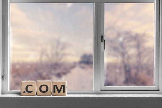 Com sign in a bright window with a view to a road going through a landscape