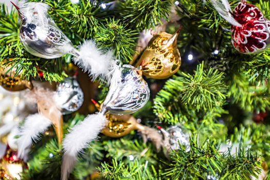 Christmas tree with bird baubles in silver glass in shiny lights