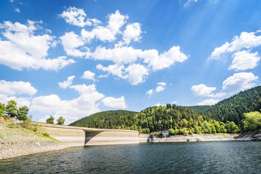 Lake landscape with a dam in summer with a forest in the background