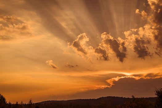 Sunset with rays lighten up the clouds in a countryside