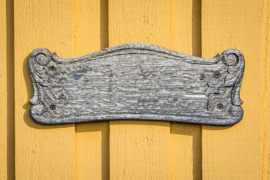 Wooden vintage sign on yellow planked wall in the sun