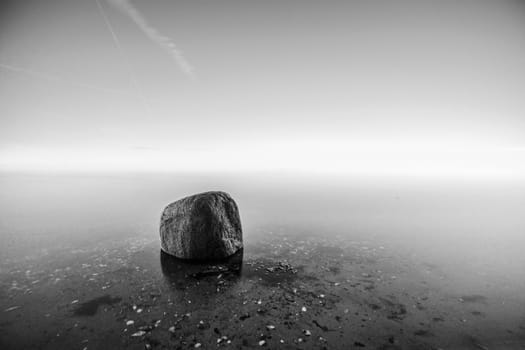 Single rock in the water by the sea in black and white colors