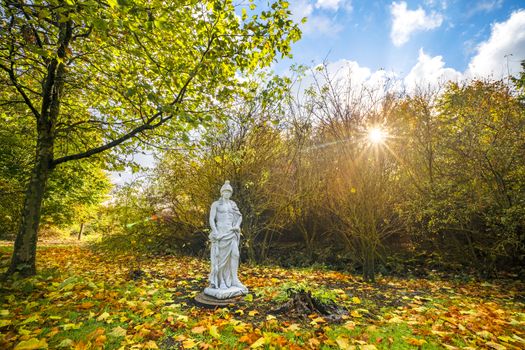 Sculpture in a park with colorful autumn leaves on the ground in the fall