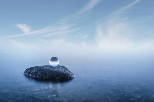Crystal ball on a rock in a misty seascape with calm blue waters