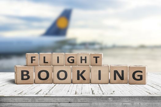 Flight booking sign at an airport with a plane in the background