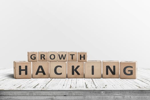 Growth hacking sign on a wooden desk with a grey wall in the background