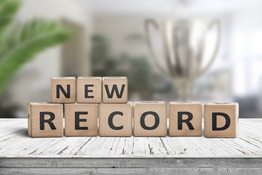 New record sign on a wooden table in a bright room with green plants and a trophy