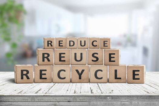 Reduce, reuse and recycle sing on a wooden desk woth a fresh bright background