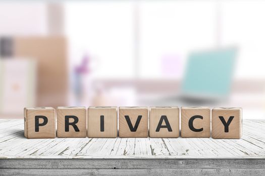 Privacy sign on a wooden table in a bright room with a computer