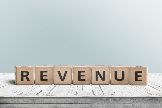 Revenue sign on a wooden desk with a light blue wall in the background