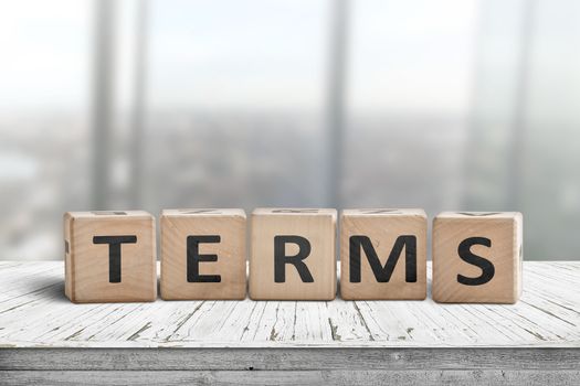 Terms sign in a bright office on a wooden desk with windows in the background