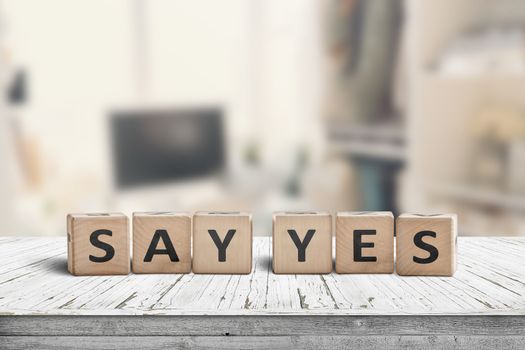 Say yes sign on a wooden desk in a bright room with a blurry background