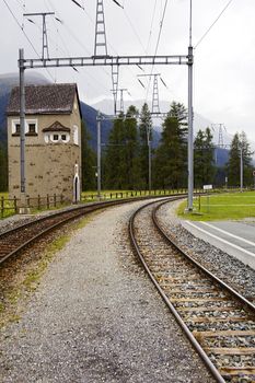 Old narrow gauge railway in the valley of the Alps among the trees in cloudy weather.